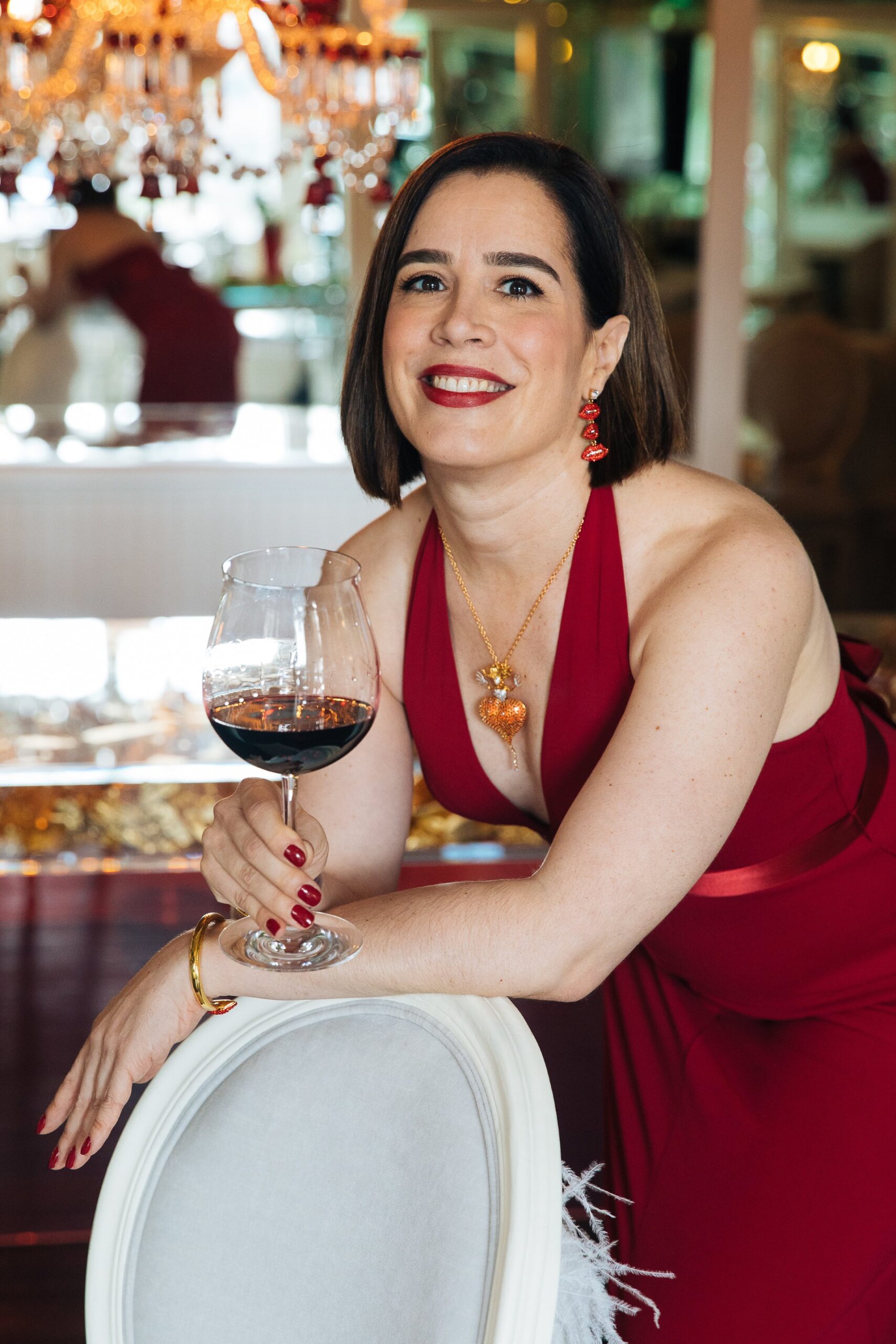 Marnie holding a wine glass in a red dress.